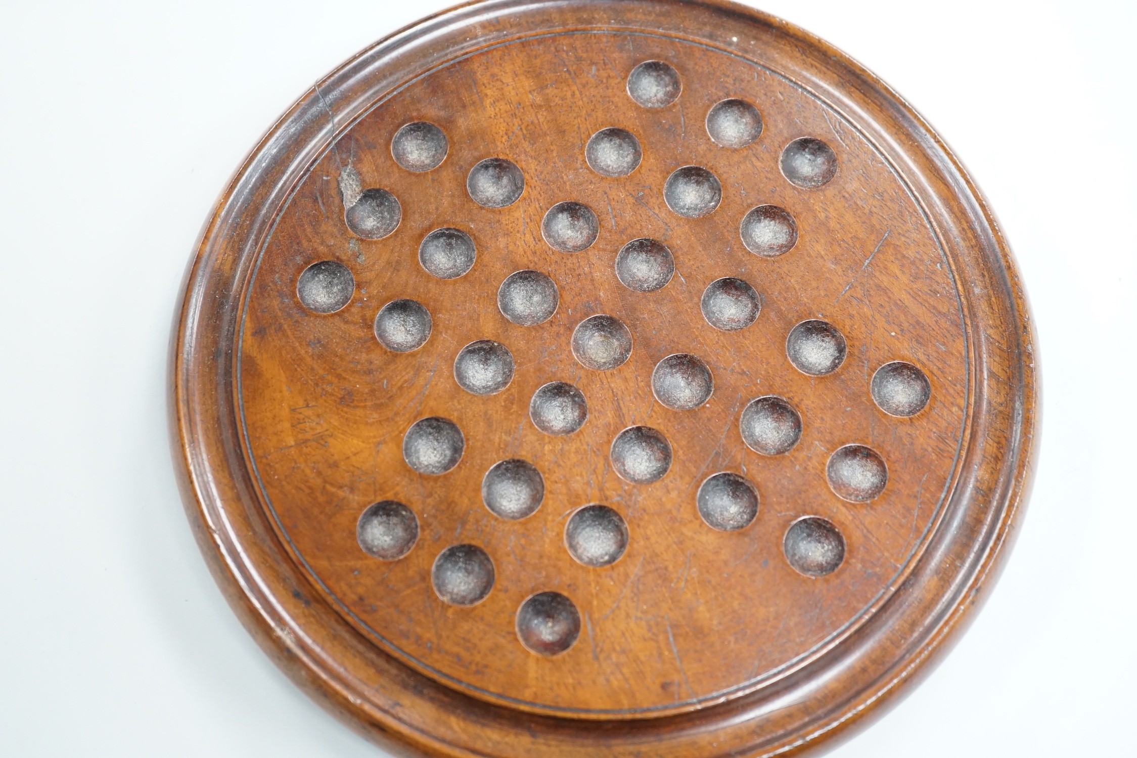 A mahogany solitaire board with a collection of latticino and marbled glass marbles